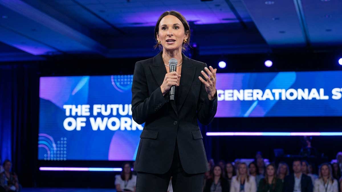 Natalie Marshall speaking at a business conference on stage with a microphone